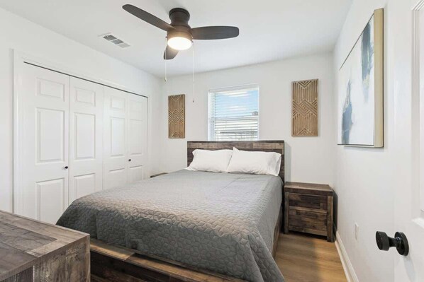 A bedroom with a bed, a ceiling fan, a window, and a door. - 3 bed 2 bath Nola home (Meraux)