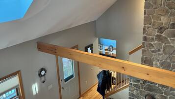 Une pièce de style « loft », dotée d’une lucarne, d’une cheminée en pierre et d’un escalier en bois.