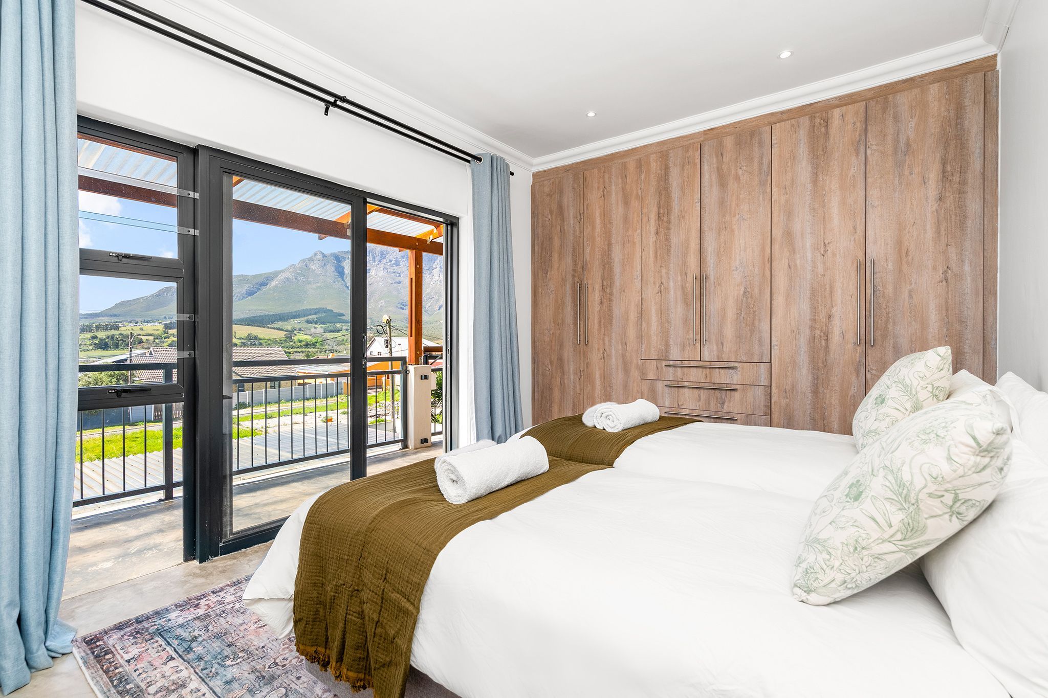A hotel room with a bed, a wooden wardrobe, a balcony with a view of the countryside.