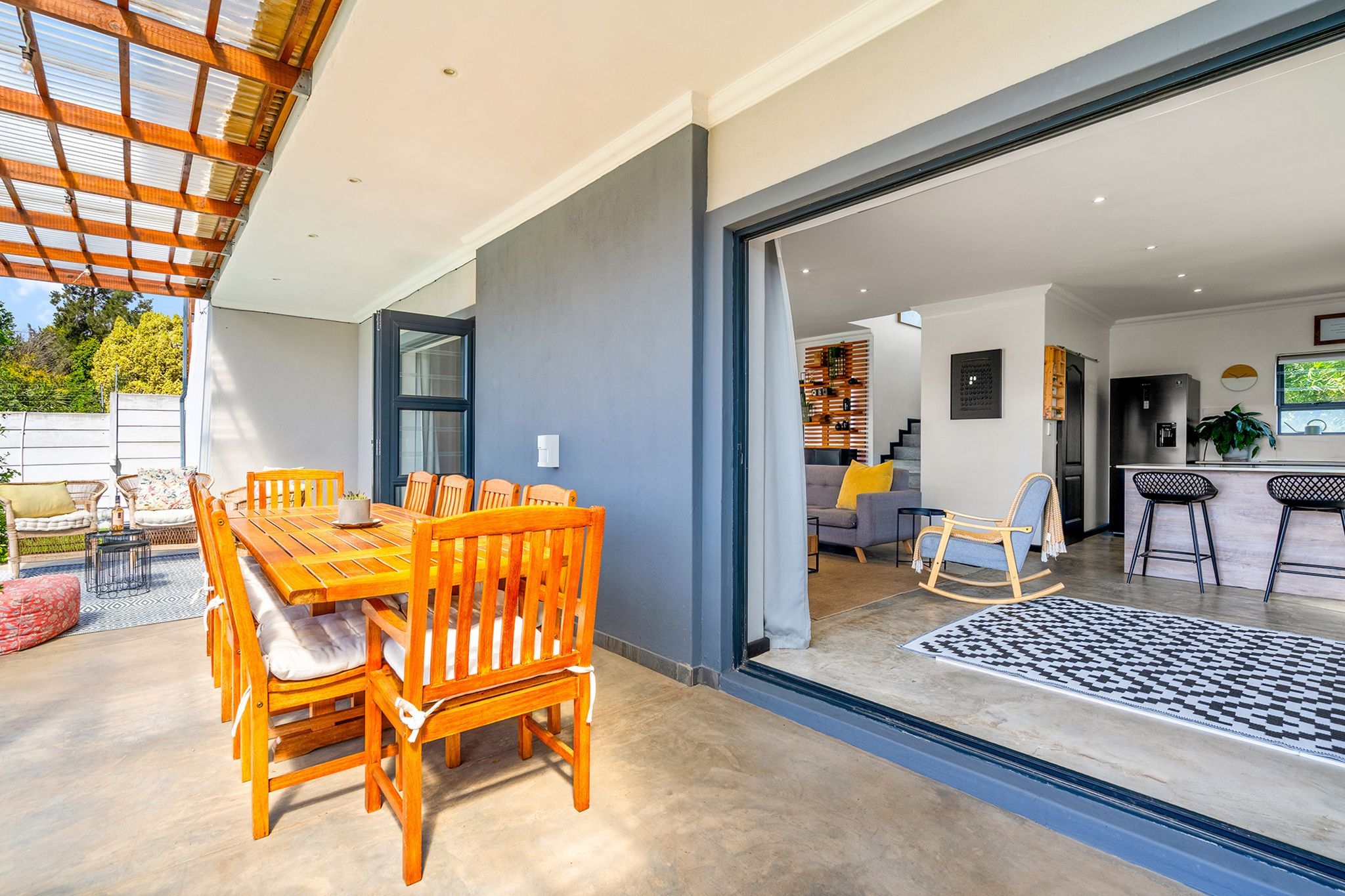 A modern kitchen with a bar area, a dining area with wooden furniture, and a view of the outdoors.