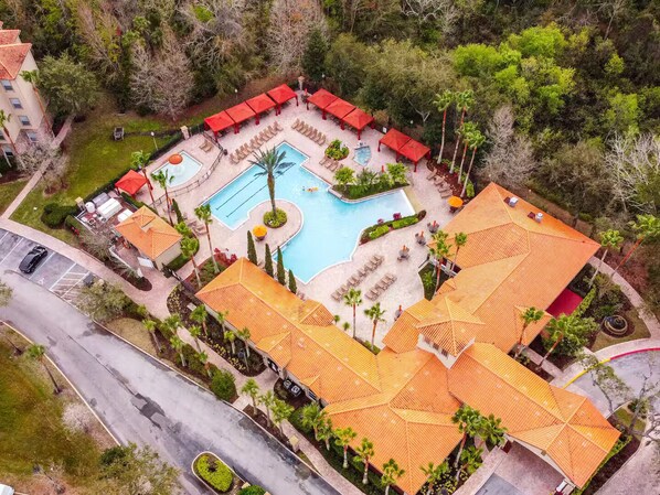 An aerial view of a resort with a swimming pool, sun loungers, and a covered patio area. - 3BR Disney Oasis /Sleeps 8 /No Fees (Davenport)