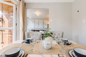 A dining table set with plates, glasses, and a vase of flowers. - 3 Bedroom |City Centre | Modern  with Balcony (Manchester)