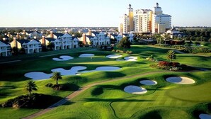 A golf course with bunkers, a clubhouse, and residential buildings in the background. - Sleek 3-Bed Oasis in Reunion with Golf view (Kissimmee)