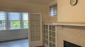 A room with a fireplace, a clock on the wall, and a door leading to a balcony. - Modern 2BR • 2 King Beds • Near Bakery Sq, Downtown & Universities (Pittsburgh)