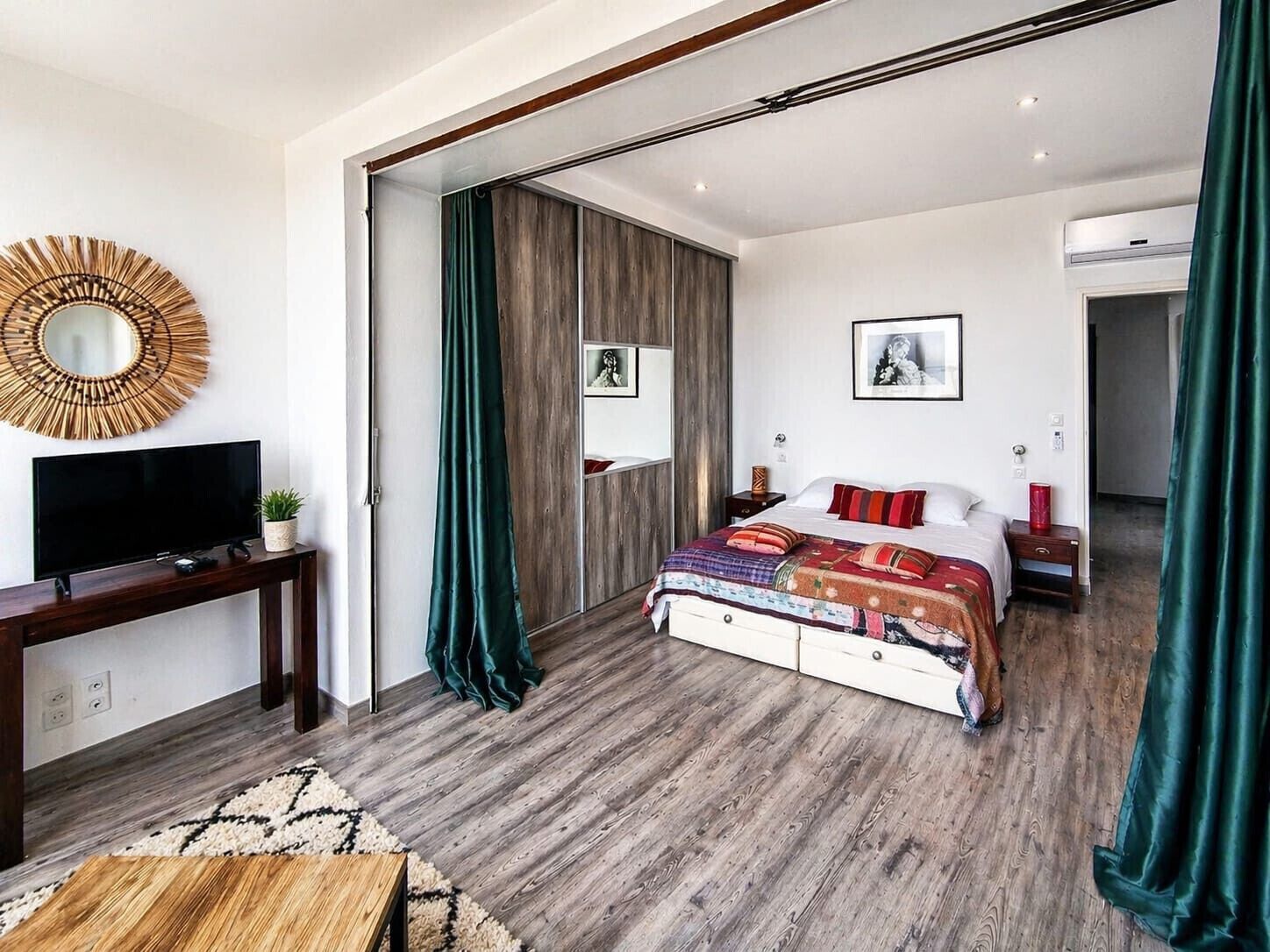 Una camera da letto moderna con un letto, una TV, uno specchio e un armadio.