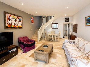 A living room with a TV, sofa, coffee table, and a staircase leading to another room. - REF ESTEREL BY PALMES D OR PROPERTIES (Mandelieu-la-Napoule)