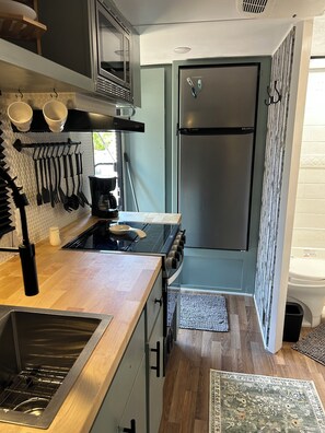 Eine kleine Küche mit Herd, Spüle und Kühlschrank.