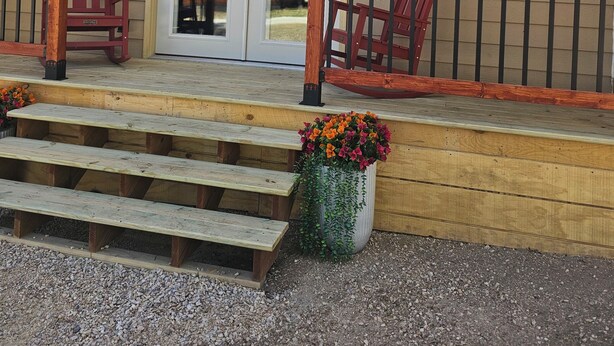 A wooden building with a porch, a horse sculpture, and a set of steps leading to a door.