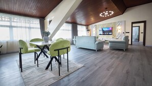 Una sala de estar moderna con comedor, techo de madera y televisor de pantalla plana.