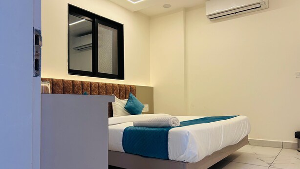 Ein modernes Hotelzimmer mit Bett, Klimaanlage und einem Fenster mit Jalousien.