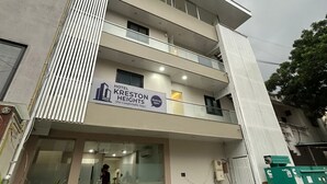 Ein mehrstöckiges Hotel mit einem Schild, auf dem 'Hotel Kreston Heights' und 'Buchungseröffnung' steht.