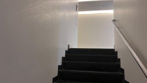 Eine Treppe mit Metallgeländer, das zu einer Zwischenebene führt.