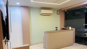Ein Empfangsschalter mit an der Wand befestigtem Flachbildfernseher, Deckenventilator und Klimaanlage.