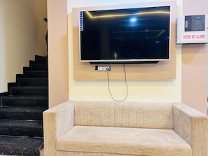 Una sala de estar con un televisor de pantalla plana en la pared, un sofá y una escalera.
