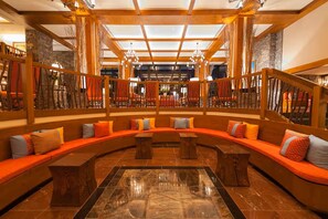 A spacious lobby with a curved seating area, wooden beams, and a stone wall.