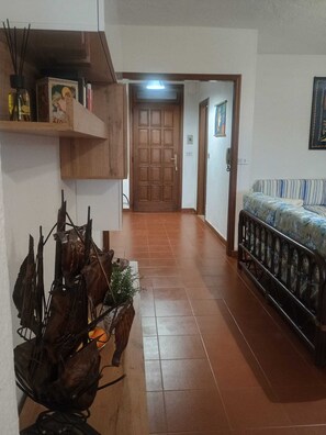 A hallway with a wooden door, a sofa, and a shelf with decorative items. - Garden tranquility ideal for children and animals, for those who love mountain biking (Finale Ligure)