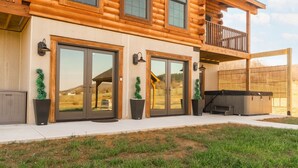 A log cabin with large sliding glass doors, a balcony, and a patio area. - Brand New Cabin w Hot Tub, Fishing Pond, Firepit (McHenry)