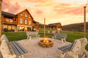 A wooden cabin with a fire pit, outdoor seating, and string lights. - Brand New Cabin w Hot Tub, Fishing Pond, Firepit (McHenry)