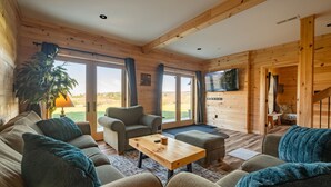 A cozy cabin interior with a sofa, armchair, and a coffee table. - Brand New Cabin w Hot Tub, Fishing Pond, Firepit (McHenry)