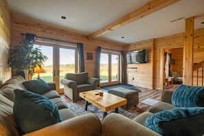 A cozy cabin interior with a sofa, armchair, and a coffee table. - Brand New Cabin w Hot Tub, Fishing Pond, Firepit (McHenry)