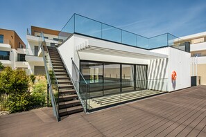 A modern building with a glass balcony, a staircase, and a clear sky.