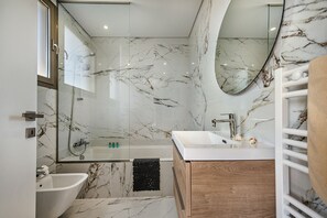 A modern bathroom with a bathtub, a sink, a mirror, and a wooden vanity.