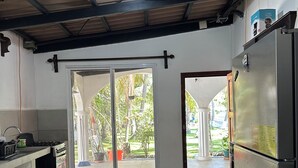 Cozinha com fogão a gás, geladeira e porta de vidro deslizante que dá para um pátio.