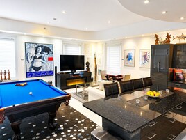 Una sala de estar moderna con mesa de billar, televisor de pantalla plana y comedor con mesa de granito negro.