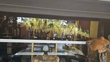 Een eethoek met een glazen tafel, omringd door stoelen, een grote decoratie van een dieren schedel, en uitzicht op een terras.