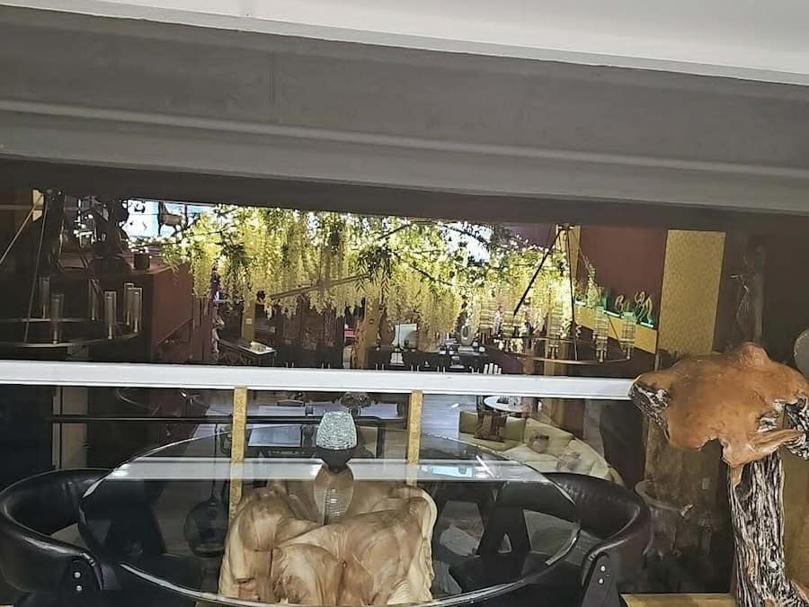 Un comedor con una mesa de vidrio rodeada de sillas, una decoración con cráneo de animal y vistas a una zona de estar al aire libre.