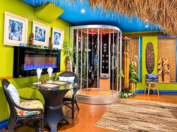 Una habitación con una mesa de vidrio, sillas, un televisor y un separador circular de vidrio.