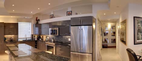 A modern kitchen with a curved island, stainless steel appliances, and recessed ceiling lighting.