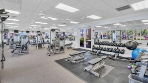 Ein Fitnessstudio mit verschiedenen Trainingsgeräten, Spiegeln und Blick nach draußen.