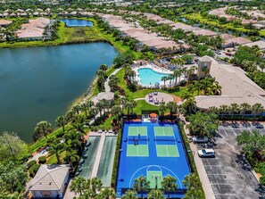 An aerial view of a resort with a central swimming pool, tennis courts, and a lake. - Luxury Palmer Ranch Home-Siesta Key, Pickleball & Pool (Sarasota)