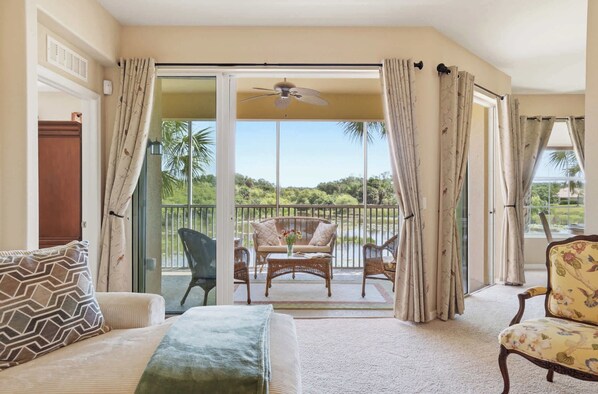 A room with a sofa, a chair, a table with a vase, and a balcony with a view of greenery. - Luxury Palmer Ranch Home-Siesta Key, Pickleball & Pool (Sarasota)