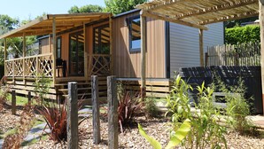 Una estructura de madera con porche cubierto, jardín cercado y jacuzzi.