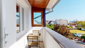 A balcony with a table and chairs, a window, and a view of neighboring houses. - Little ingersheim near Colmar (Ingersheim)