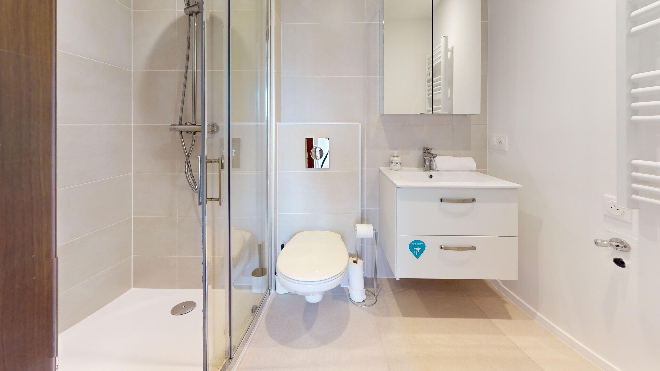 Un baño moderno con cabina de ducha de vidrio, inodoro, lavamanos y espejo.