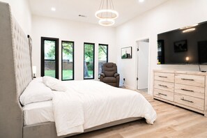 Een slaapkamer met een groot bed, een houten dressoir, een stoel en een televisie.
