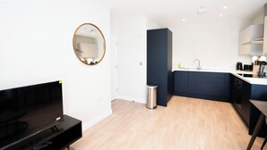 A modern kitchen with a sink, cabinets, and a television. - Church House by Guestz (Filton)