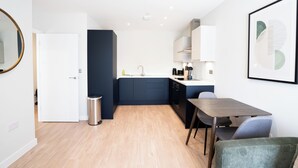 A compact kitchen with a sink, stove, and cabinets, a dining area with a table and chairs, and a door leading to another room. - Church House by Guestz (Filton)
