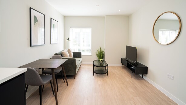 A modern living room with a dining area, a sofa, a TV stand, and a large mirror. - Church House by Guestz (Filton)