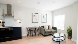 A modern kitchen with built-in appliances, a dining area with a table and chairs, a sofa, and a round coffee table. - Church House by Guestz (Filton)