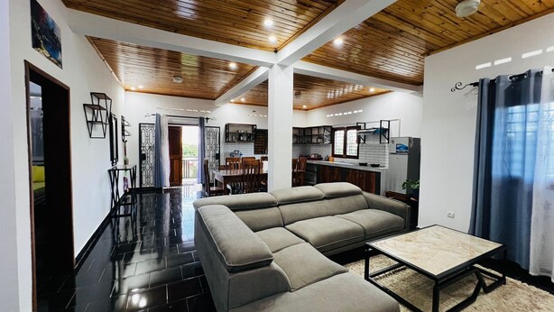 A modern living space with a sectional sofa, a dining area, and a kitchen. - Apartment no. 4 (Antsiranana)