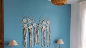 Un dormitori amb una paret blava, un llit blanc, dues làmpades de nit i una decoració de penjador de somnis.