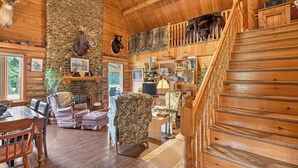 A log cabin interior with a stone wall, wooden staircase, and mounted animal heads. -  Waterfront Log Cabin for Nature Lovers,moments with family friends, Spa Sleep 8 (Wayerton)