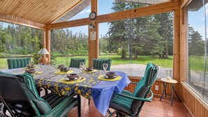 A wooden-paneled room with a dining table set for four, chairs, a clock, and a view of a forest. -  Waterfront Log Cabin for Nature Lovers,moments with family friends, Spa Sleep 8 (Wayerton)