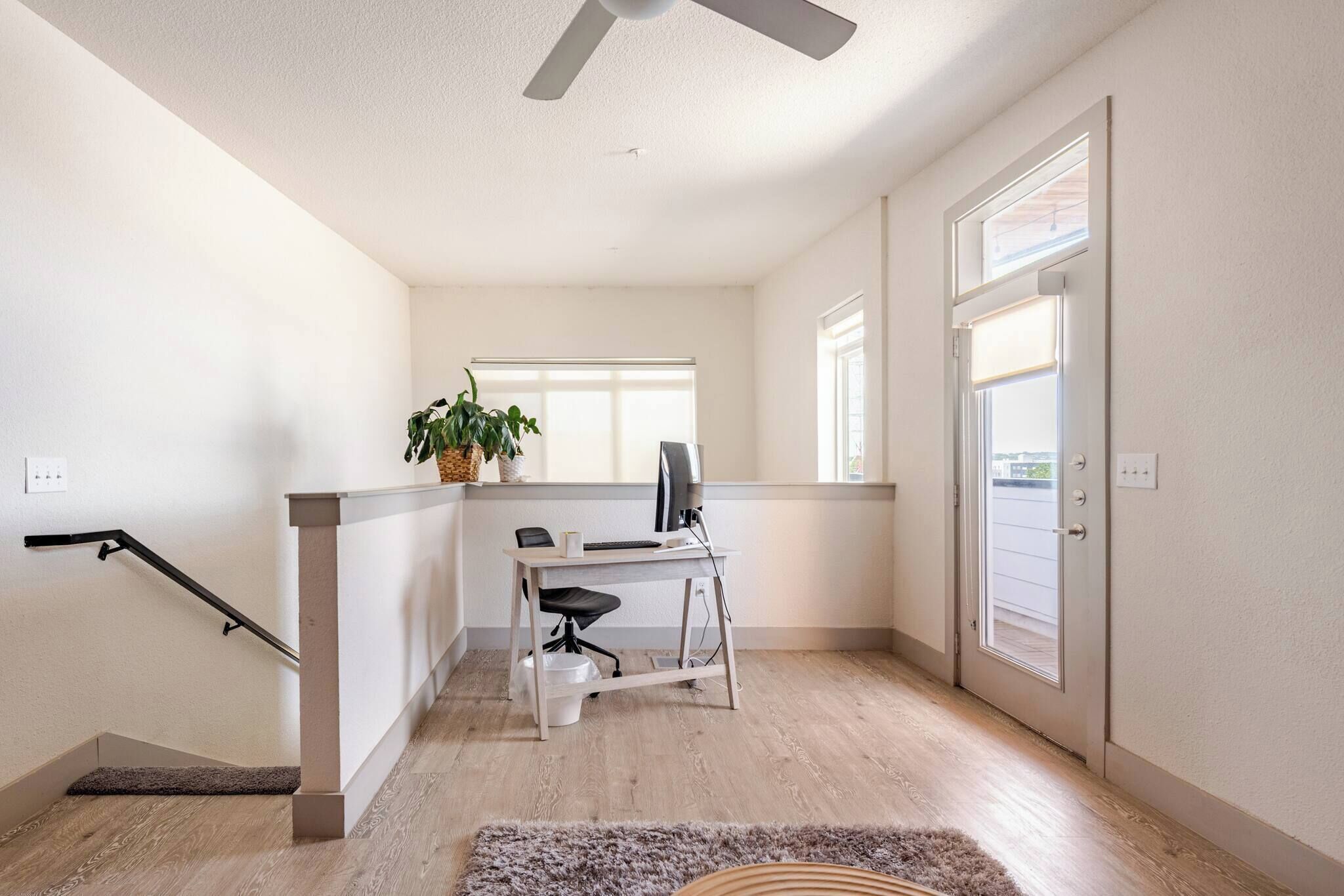 Ein modernes Zimmer mit Schreibtisch, Stuhl und Deckenventilator.
