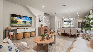 Un salon moderne avec un grand tableau, un coin repas et un escalier.