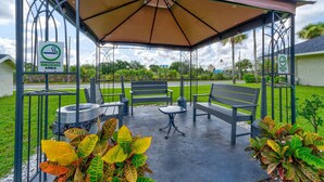 A designated smoking area with benches and tables under a canopy. - The Mickey and Minnie studio w/ pool & parking (Kissimmee)